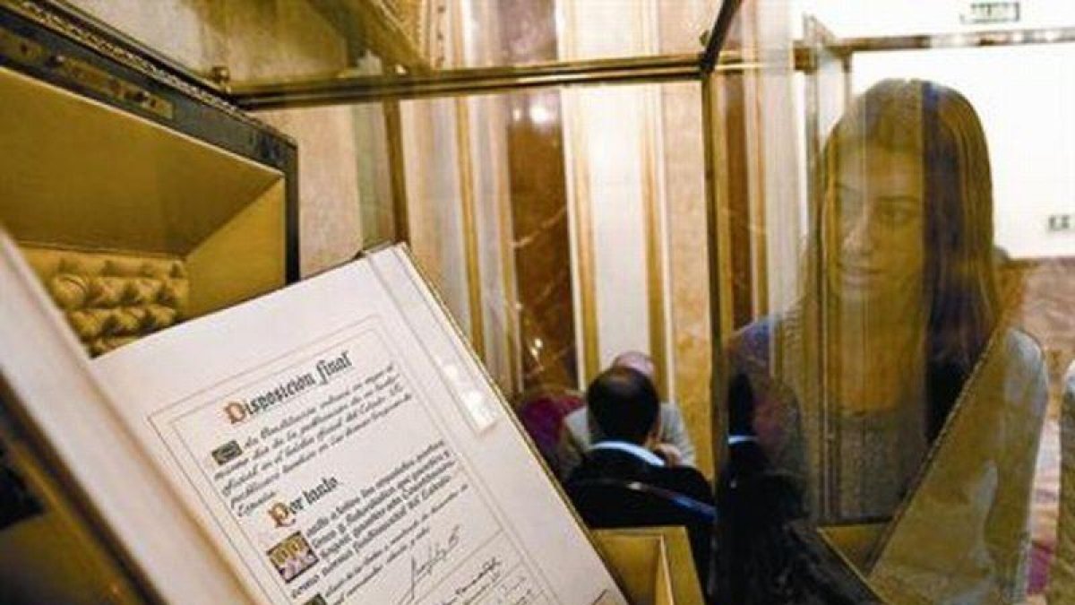 Una empleada del Congreso de los Diputados contempla, ayer, el ejemplar único del texto original de la Constitución, firmado por el Rey y los presidentes de las dos cámaras legislativas durante la sesión solemne que tuvo lugar el 27 de diciembre de 1978.-JUAN MANUEL PRATS