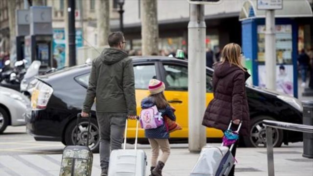 Unos turistas se dirigen a una parada de taxis en Barcelona.-FERRAN NADEU