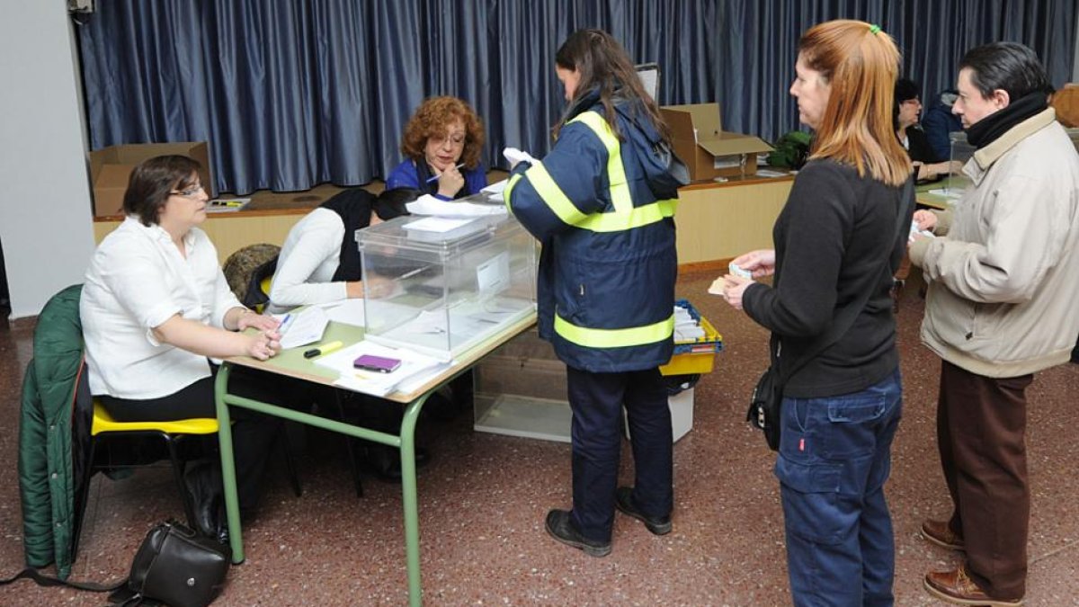 Una empleada de Correos deposita los votos por correo en una de las mesas electorales.-ISRAEL L. MURILLO