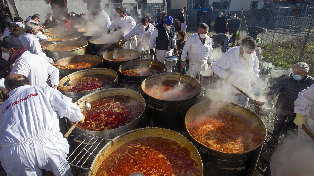 Varios cofrades cocinan los titos en varias las calderas mientras los vecinos pasan a por su ración. TOMÁS ALONSO