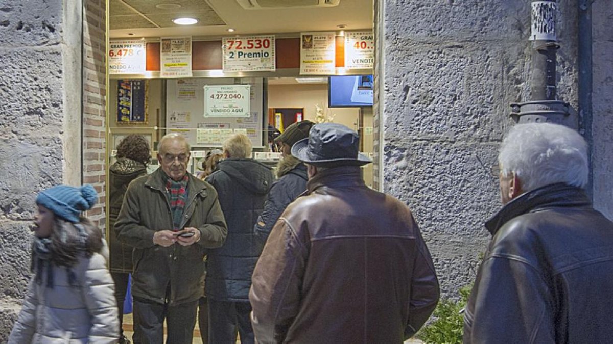 Clientes hacen cola en ‘El Gato Negro’ con el cartel al fondo del premio repartido.-ISRAEL L. MURILLO
