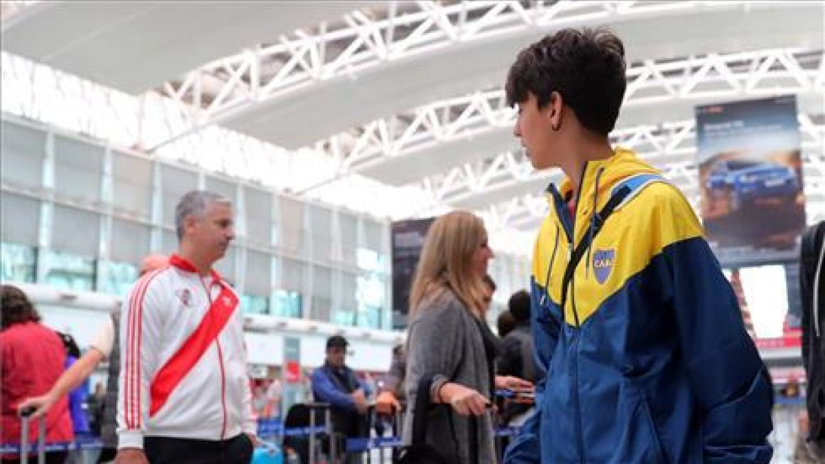 Un seguidor de River y otro de Boca, en el aeropuerto de Ezeiza, en Buenos Aires, ayer jueves.-MARCOS BRINDICCI