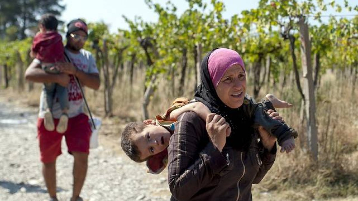 Una mujer carga con su hijo en Macedonia, este viernes.-AFP/ROBERT ATANASOVSKI