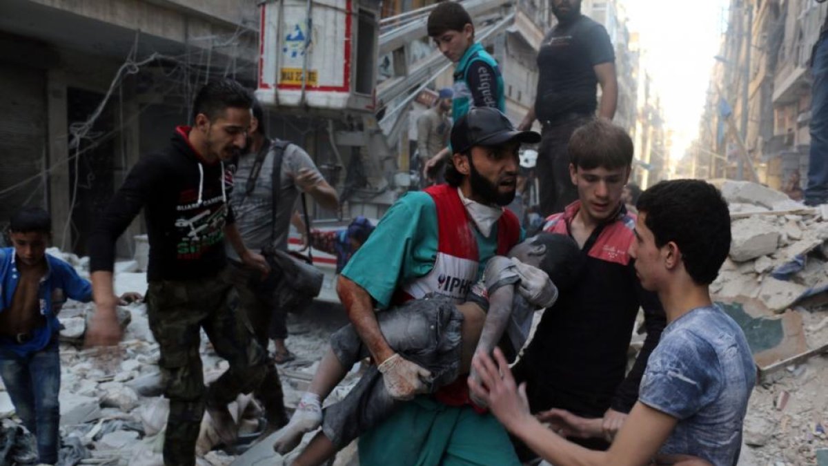 Un hombre saca el cadáver de un niño de una casa alcanzada por un bombardeo en Alepo.-AMEER ALHALBI / AFP