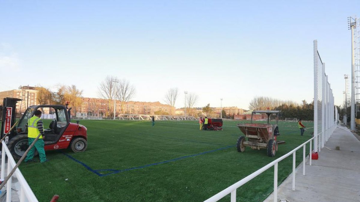 Un grupo de trabajadores instala la nueva superficie de césped artificial en el nuevo campo de San Amaro-Raúl G. Ochoa