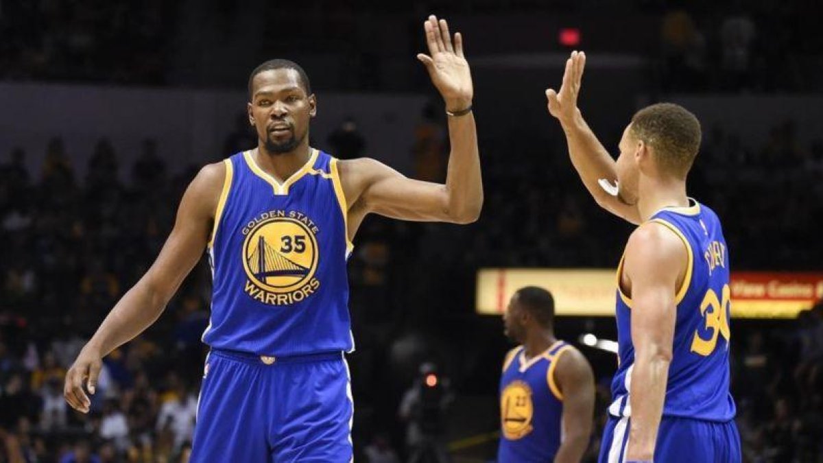 Kevin Durant choca con Stephen Curry durante un partido reciente.-AP / DENIS POROY