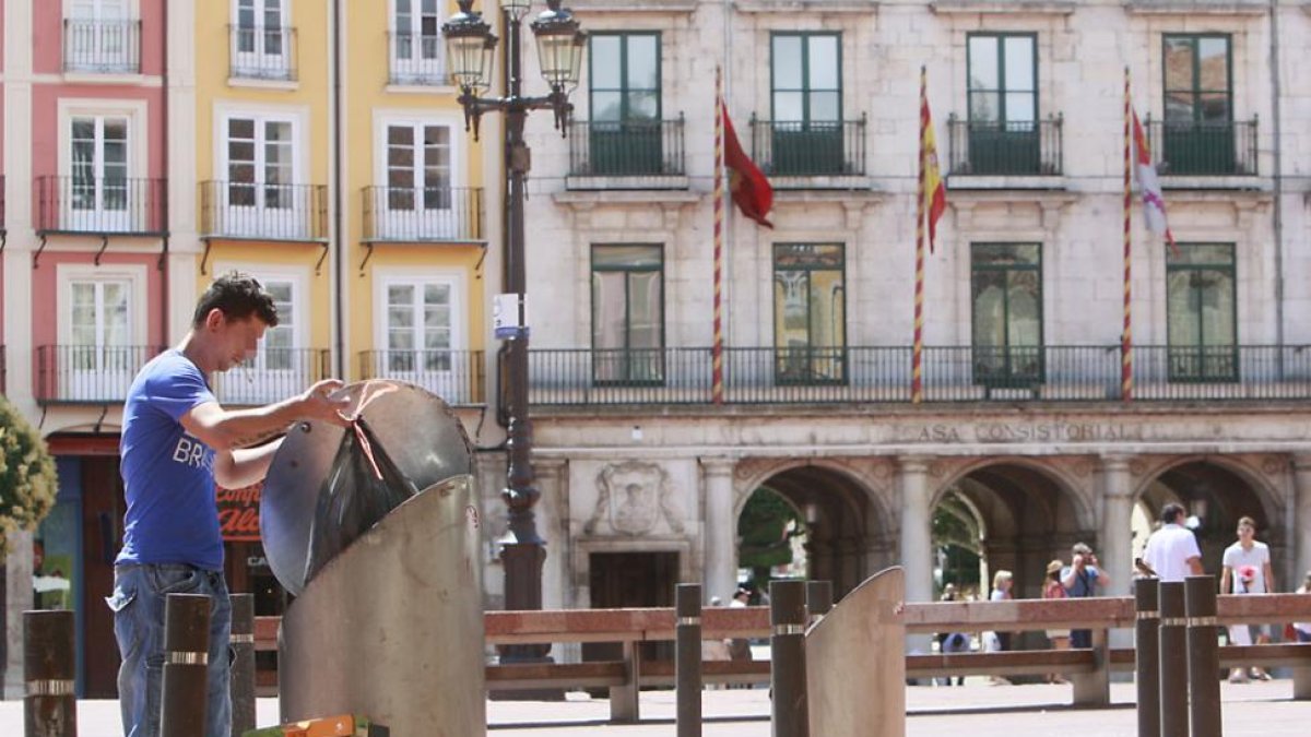 Un hombre deposita la basura en un contenedor ubicado en la Plaza Mayor.