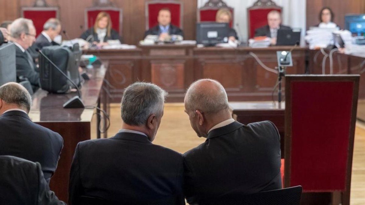 Griñán y Chaves conversan en el banquillo de los acusados, este miércoles, en el inicio del juicio por el caso ERE.-/ JULIO MUÑOZ (EFE (POOL))