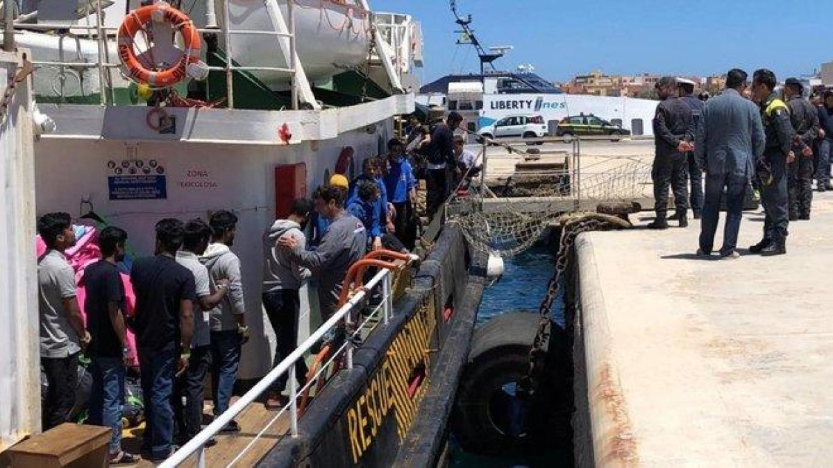 Varios inmigrantes rescatados en alta mar se disponen a desembarcar en el puerto italiano de Lampedusa.-ELIO DESIDERIO (EFE)