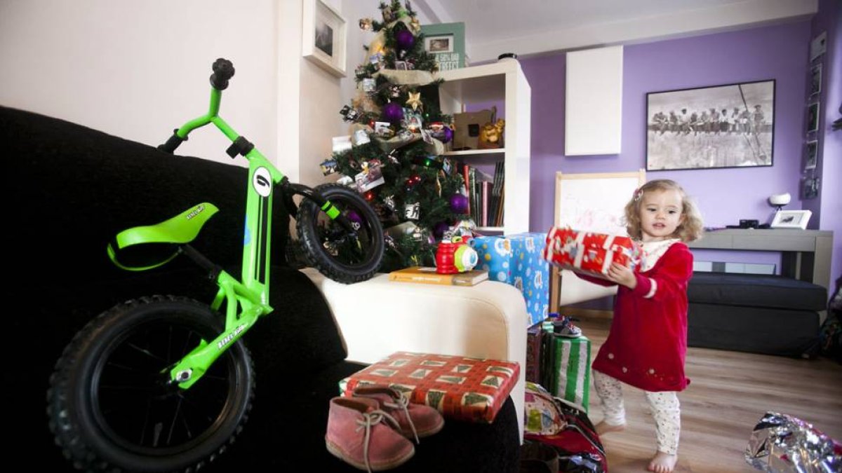 Una emocionada niña abriendo los regalos, entre ellos una bici adaptada a su edad, que le dejaron os Reyes Magos en sus zapatos la noche del 5 de enero.-SANTI OTERO