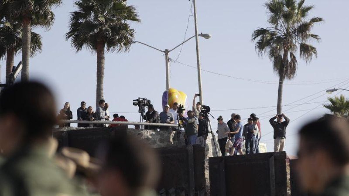 Migrantes en Tijuana, México, miran desde el otro lado del muro durante una visita de la Secretaria de Seguridad, Kirjsten Nielsen.-GREGORY BULL (AP)