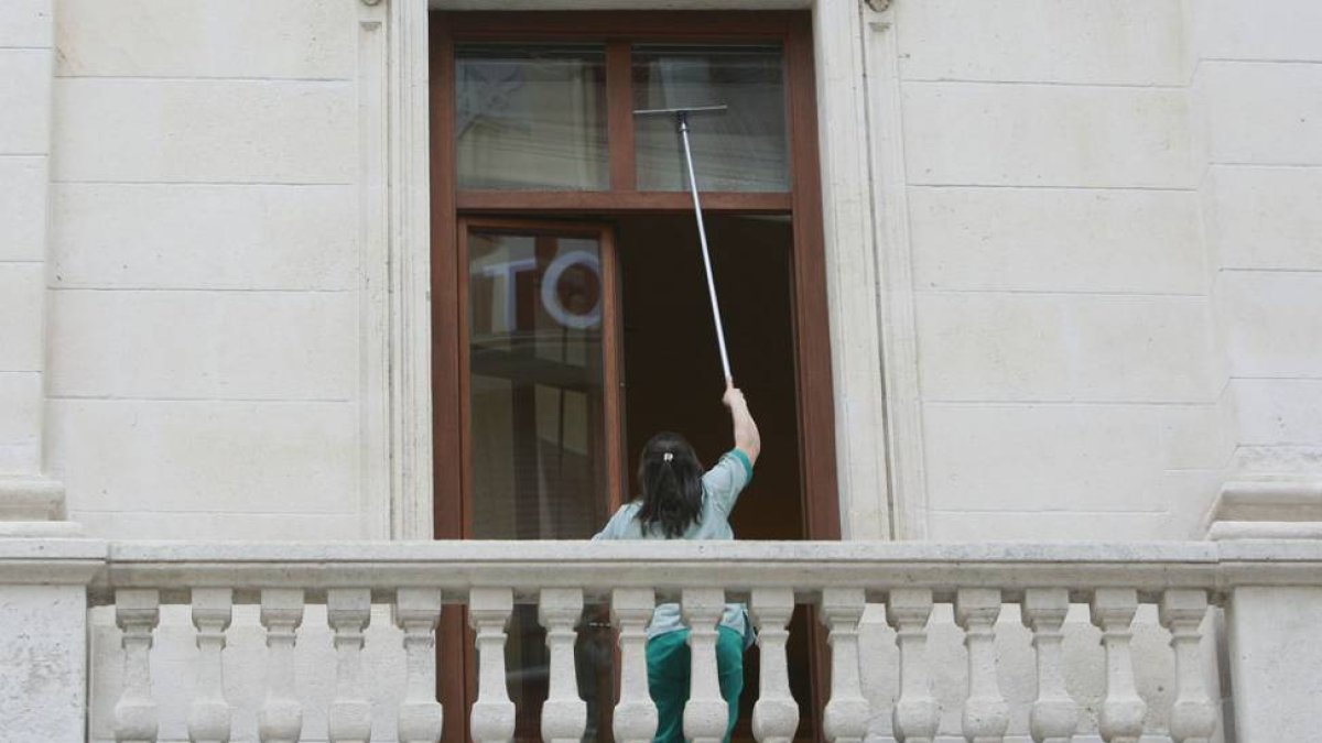 Una trabajadora limpia las ventanas de un edificio.-RAÚL OCHOA