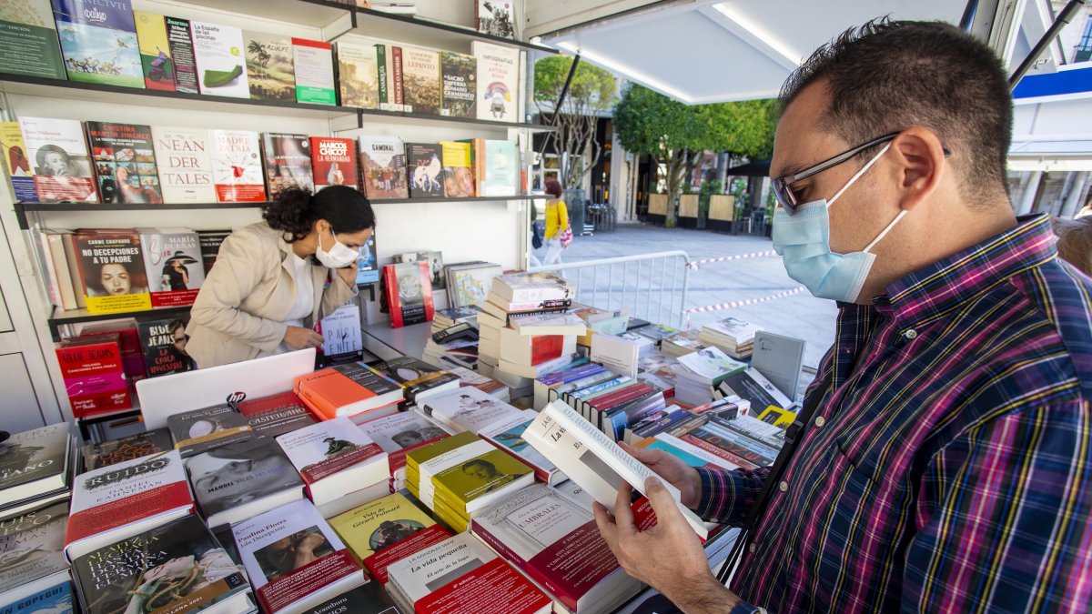 Un lector ojea un título en una de las casetas de la feria. SANTI OTERO