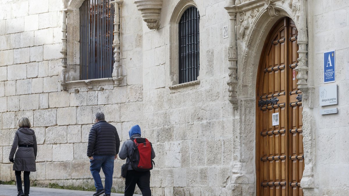 Varios viandantes pasan frente a la puerta del albergue municipal de peregrinos en la Casa del Cubo.