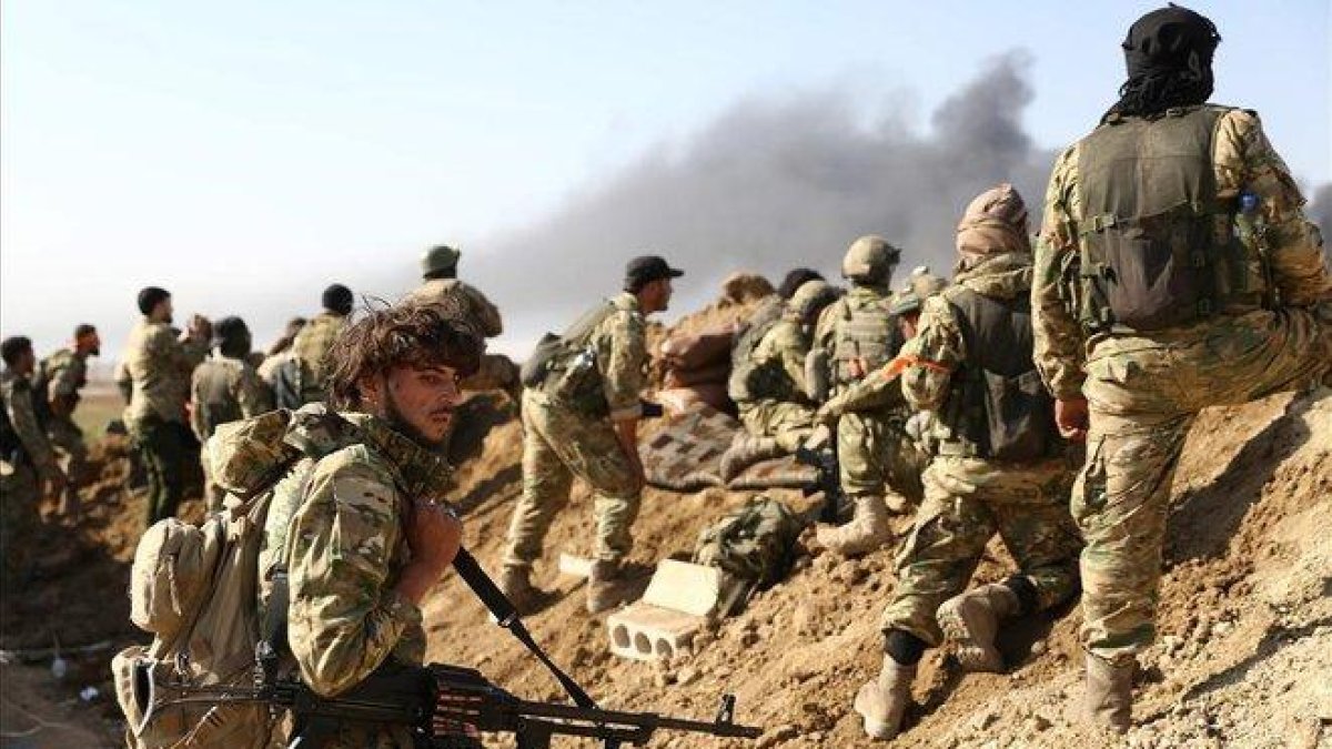 Rebeldes sirios respaldados por Turquía y soldados turcos observan las columnas de humo que se levantan desde la ciudad fronteriza de Ras al-Ain.-AFP / NAZEER AL-KHATIB
