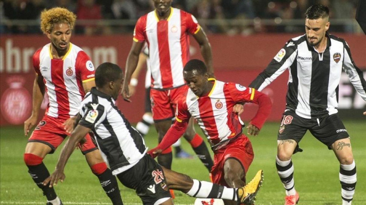 Olunga es frenado por un defensa del Levante durante el partido de Copa del jueves.-JOAN CASTRO / ICONNA