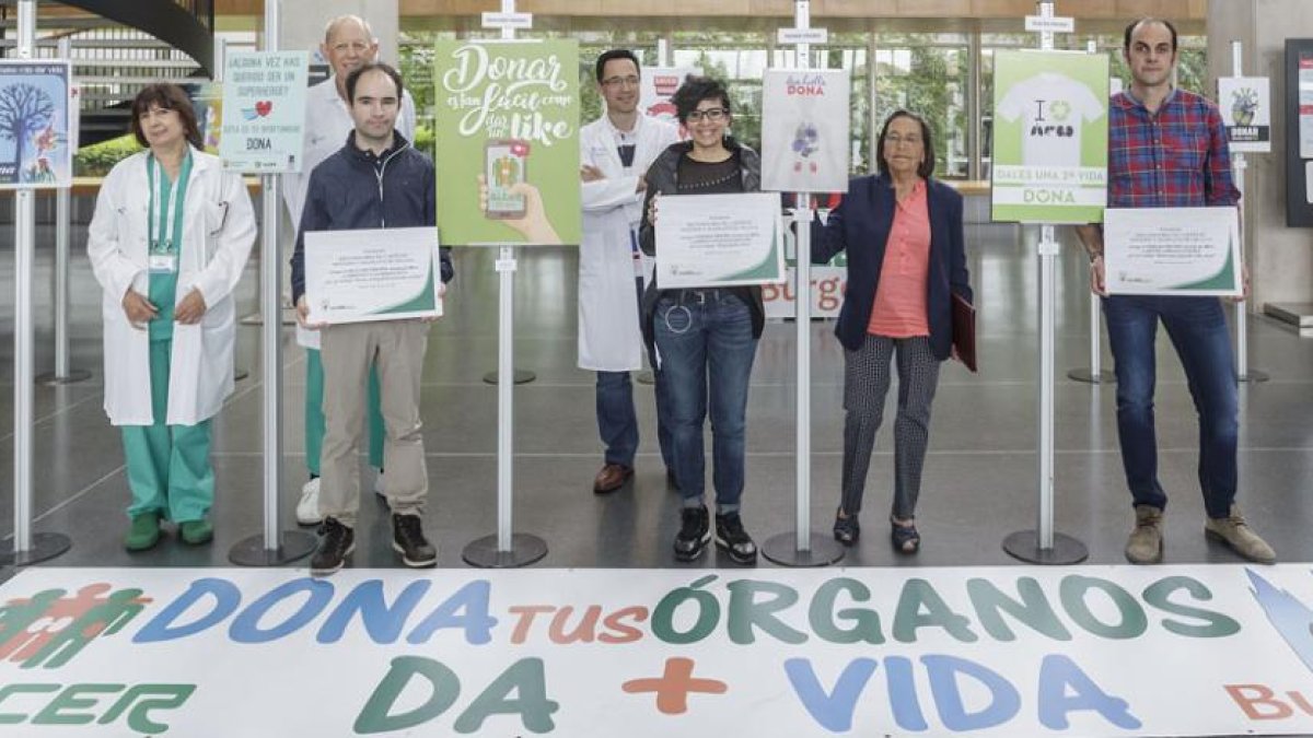 Ganadores, miembros de la asociación y profesionales del HUBU posan junto a los carteles participantes en el hall del hospital.-SANTI OTERO