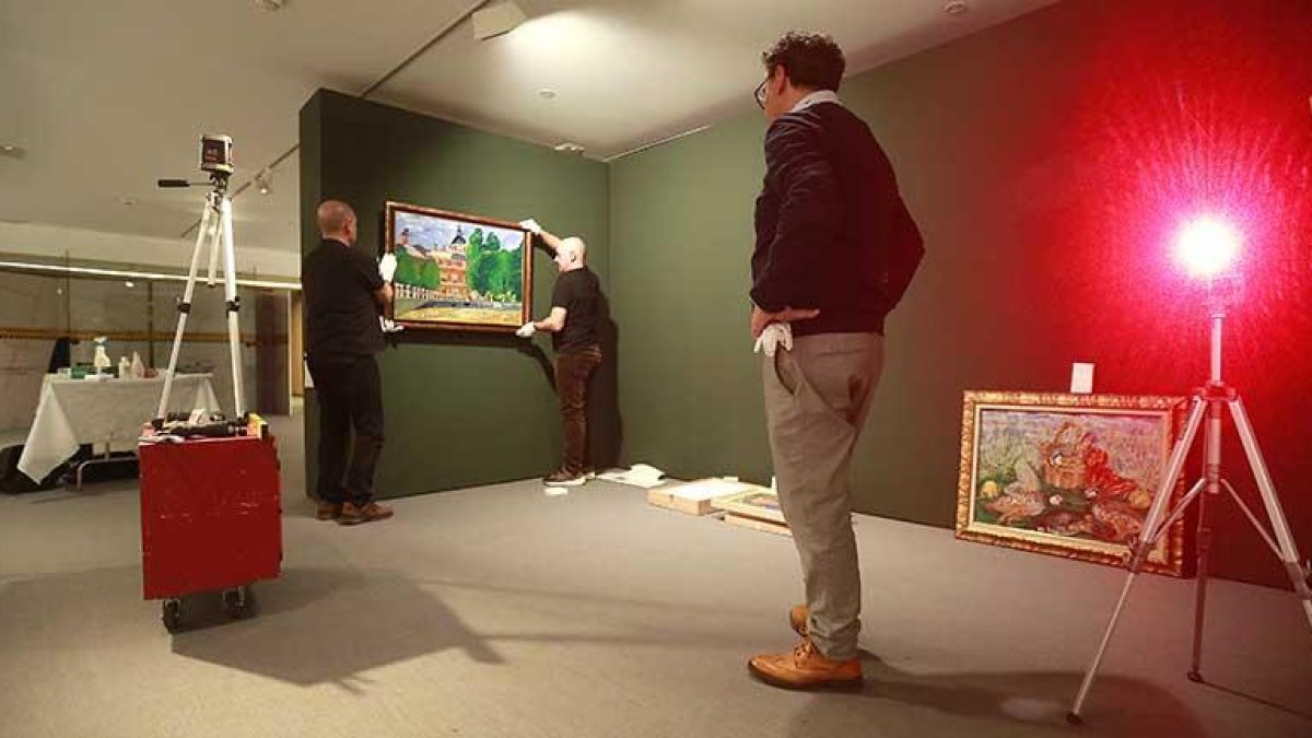 Gerardo Rubia y Julián Valle colocan una pintura bajo la mirada de Javier del Campo.-Raúl Ochoa