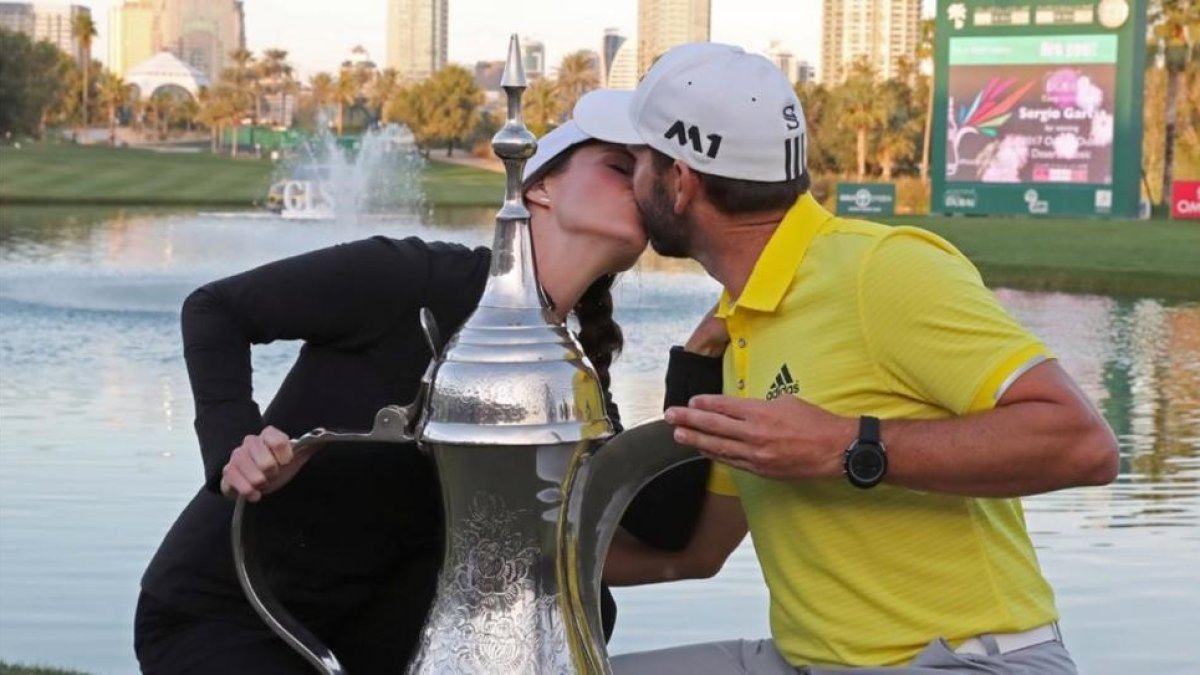 Sergio García besa a su novia, Angela Ankins, junto al trofeo del Omega Dubai Desert Classic.-AFP / KARIM SAHIB