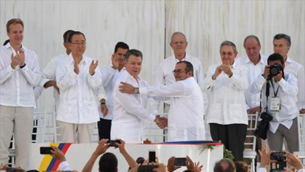 Santos y Timochenko se dan la mano entre los aplausos de Ki-mon, Castro y el rey emérito Juan Carlos, entre otras personalidades.-AFP / LUIS ACOSTA
