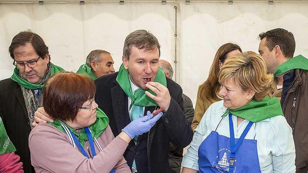 Dos de las voluntarias dan de probar la cecina al alcalde.-SANTI OTERO