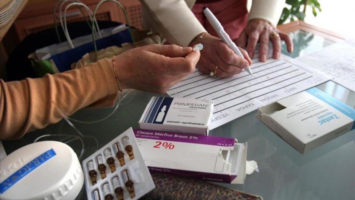 Dos enfermeras preparando los medicamentos para muerte digna en casa de un paciente.-MARC VILA