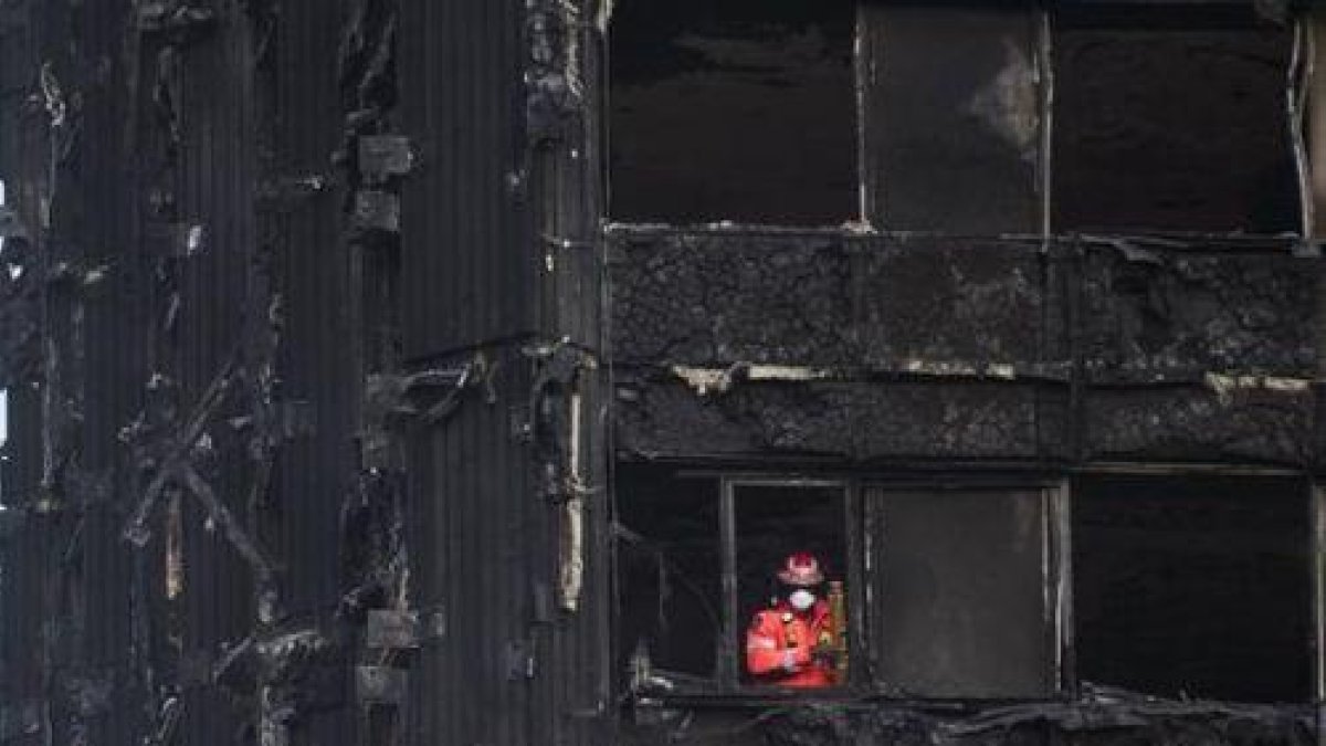Un bombero inspecciona los restos de la Torre Grenfell, el edificio de apartamentos de 24 plantas en North Kensington, que se incendió el pasado sábado.-EFE