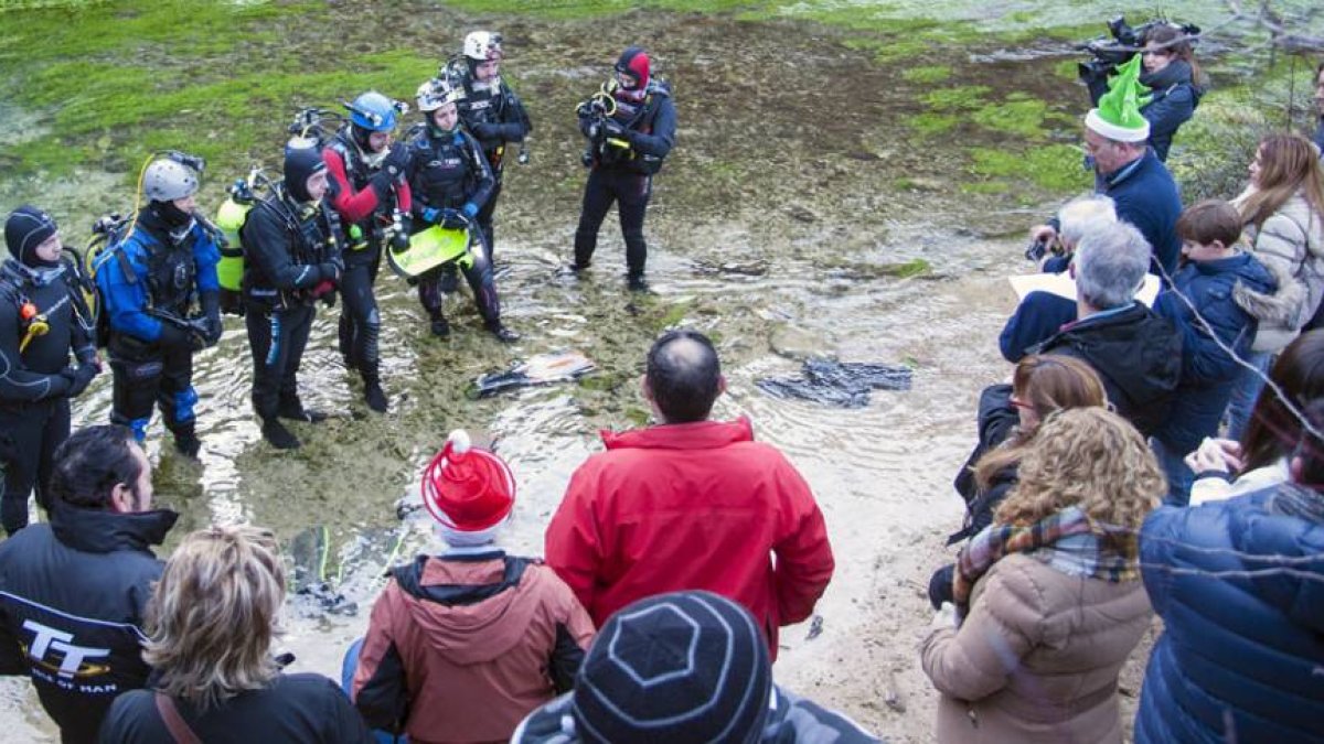 Cristina Gutiérrez sujeta el Belén en compañía de su hermano Gustavo y miembros del Club Delfín Burgos antes de proceder a sumergirse en el Pozo Azul.-Ricardo Ordóñez (Ical)