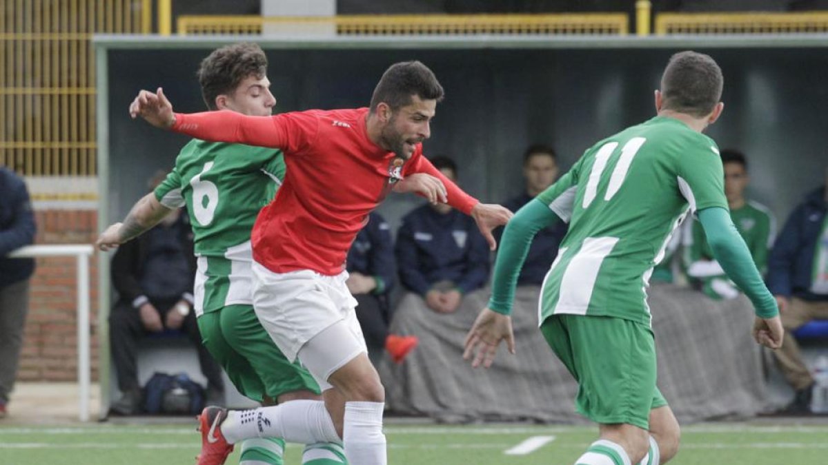 El jugador del Real Burgos Javi pugna por un esférico con dos jugadores de la Cebrereña-Santi Otero
