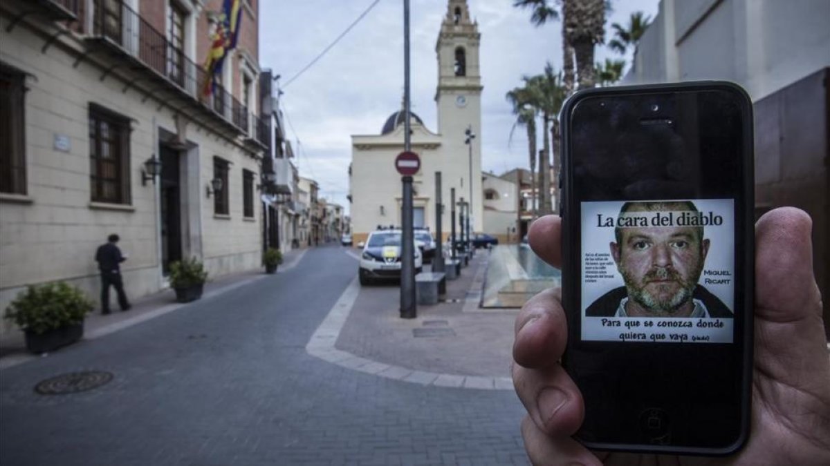 Imagen en un smartphone de Miguel Ricart, el asesino de las niñas de Alcàsser, en la plaza del ayuntamiento de la localidad valenciana.-/ MIGUEL LORENZO