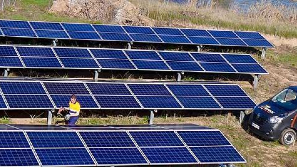 Un operario de Norsol inspecciona una batería de cuatro hileras de paneles solares junto a una balsa de riego agrícola.-ECB