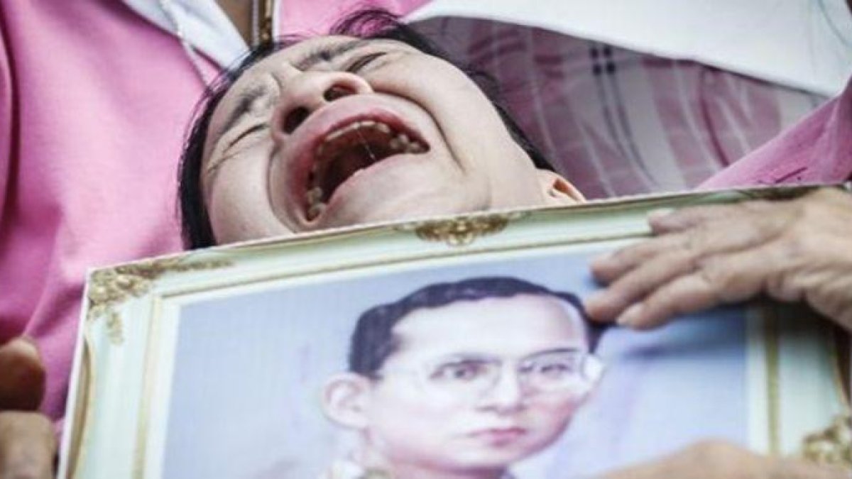 Una mujer llora a las puertas del hospital con la la foto del rey Bhumibol.-EFE / DIEGO AZUBEL