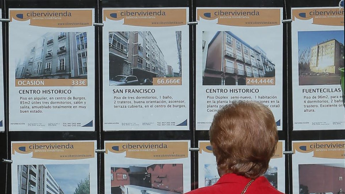 Una mujer mira anuncios de venta de inmuebles en un escaparate.-SERGIO ISAR
