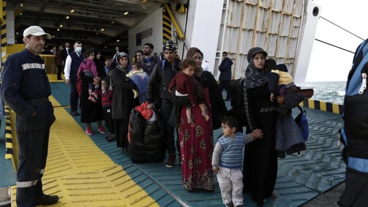 Refugiados y migrantes desembarcan del ferri 'Eleftherios Venizelos' a su llegada al puerto de Elefsina, a 20 kilómetros al noroeste de Atenas, procedentes de Lesbos, este lunes.-EFE / YANNIS KOLESIDIS