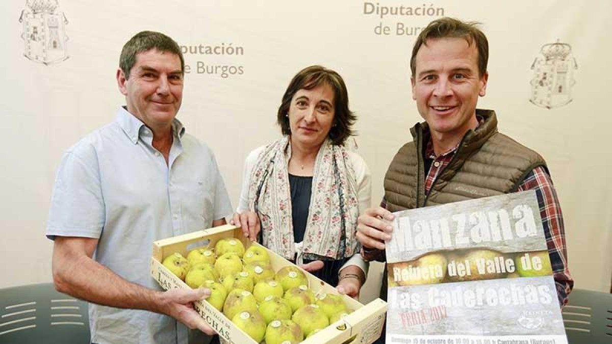 Juan José Gandía, Consuelo García y Borja Suárez posan con una caja de manzanas y el cartel de la feria.-RAÚL G. OCHOA