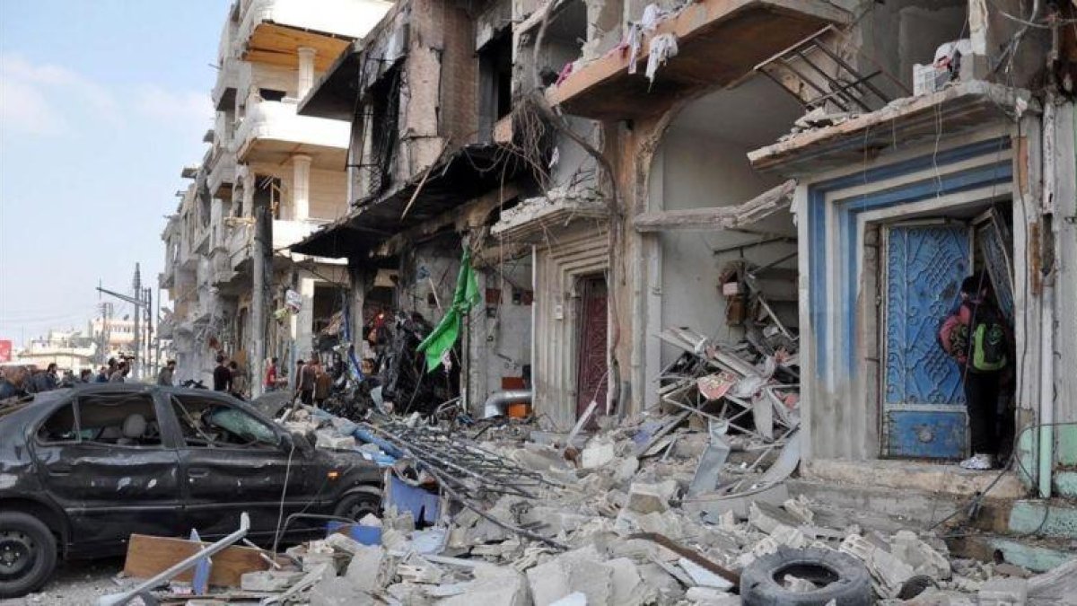 Coches y edificios destruidos cerca del lugar de un doble atentado con bomba en Homs, el 21 de febrero.-EFE