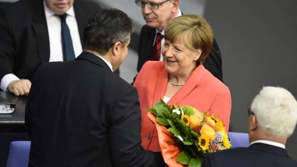 Merkel, felicitada con flores por su 61 aniversario por el vicecanciller, Sigmar Gabriel, en el Bundestag, este viernes.-Foto: AFP / TOBIAS SCHWARZ