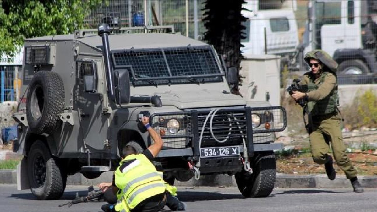 Un palestino, con un chaleco fluorescente y el distintivo de «prensa», acuchilla a un soldado israelí en Hebrón. Los soldados mataron después al agresor.-REUTERS / JAMEEL SALHAB