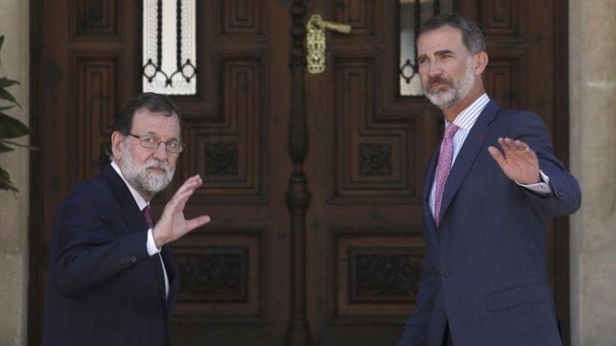 Mariano Rajoy y Felipe VI saludan a la prensa antes de entrar en el Palacio de Marivent para el almuerzo de trabajo.-EFE / BALLESTEROS