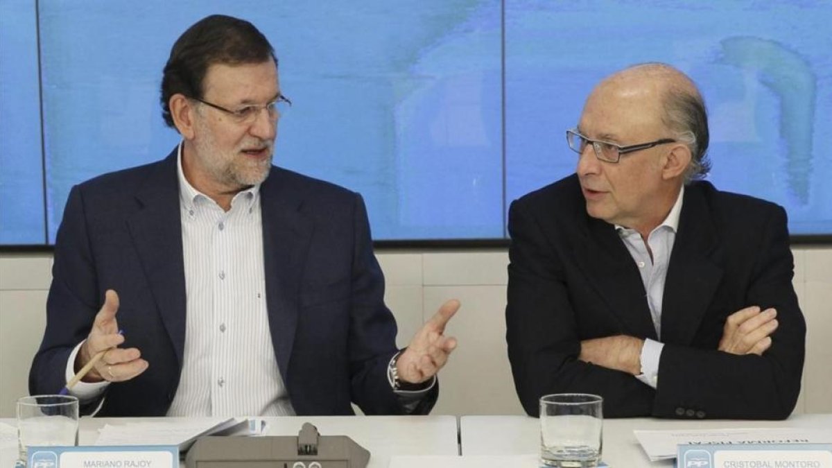 El presidente del Gobierno, Mariano Rajoy, y el ministro de Hacienda, Cristóbal Montoro, en la sede del PP en junio del 2014-PACO CAMPOS