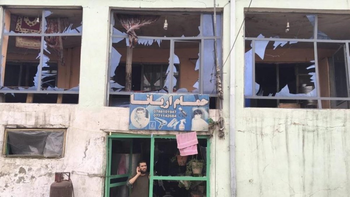 Un hombre habla por su teléfono móvil desde la entrada a su tienda dañada por un atentado cerca del Ministerio de Defensa en Kabul, Afganistán.-JAWAD JALALI