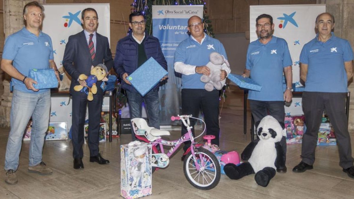 Representantes de los voluntarios, la entidad bancaria y la Diputación, con algunos de los juguetes que este año llegarán a 345 familias.-S. O.