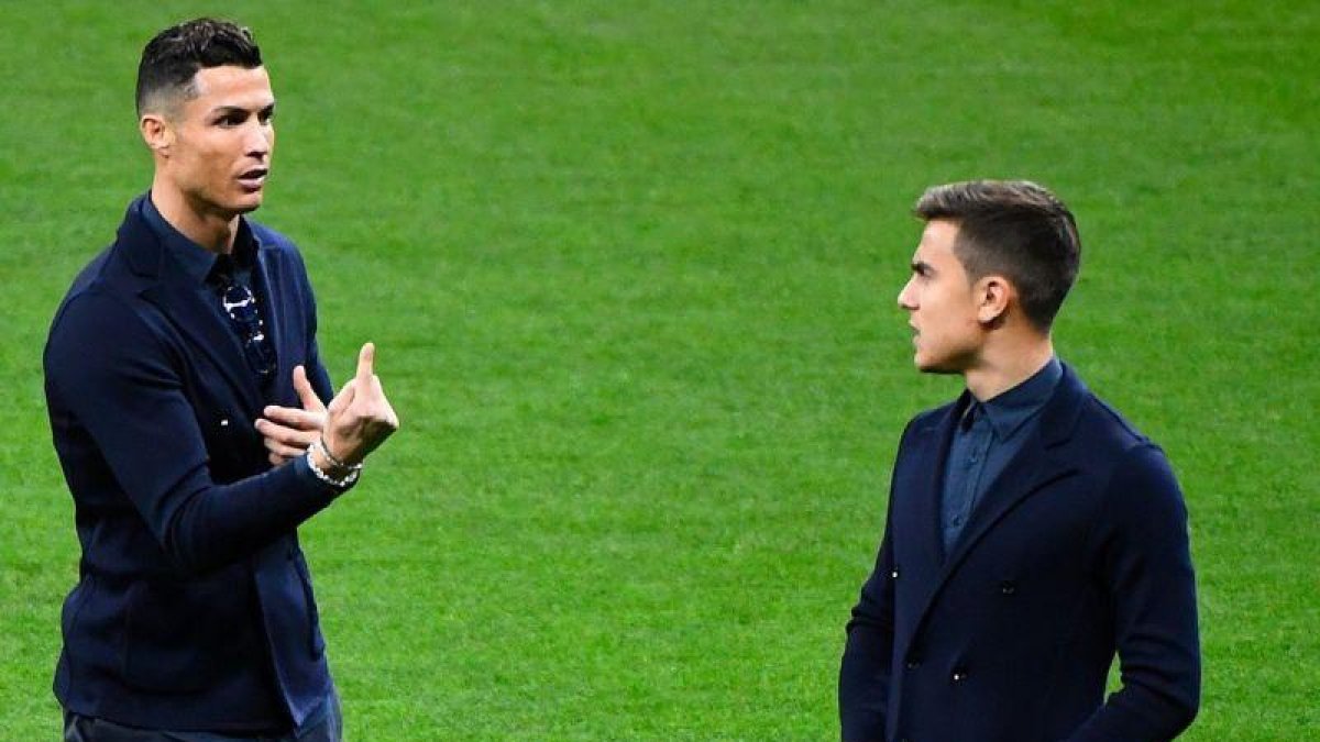 Cristiano Ronaldo (i) charla con Paulo Dybala en sobre el césped del Metropolitano.-AFP