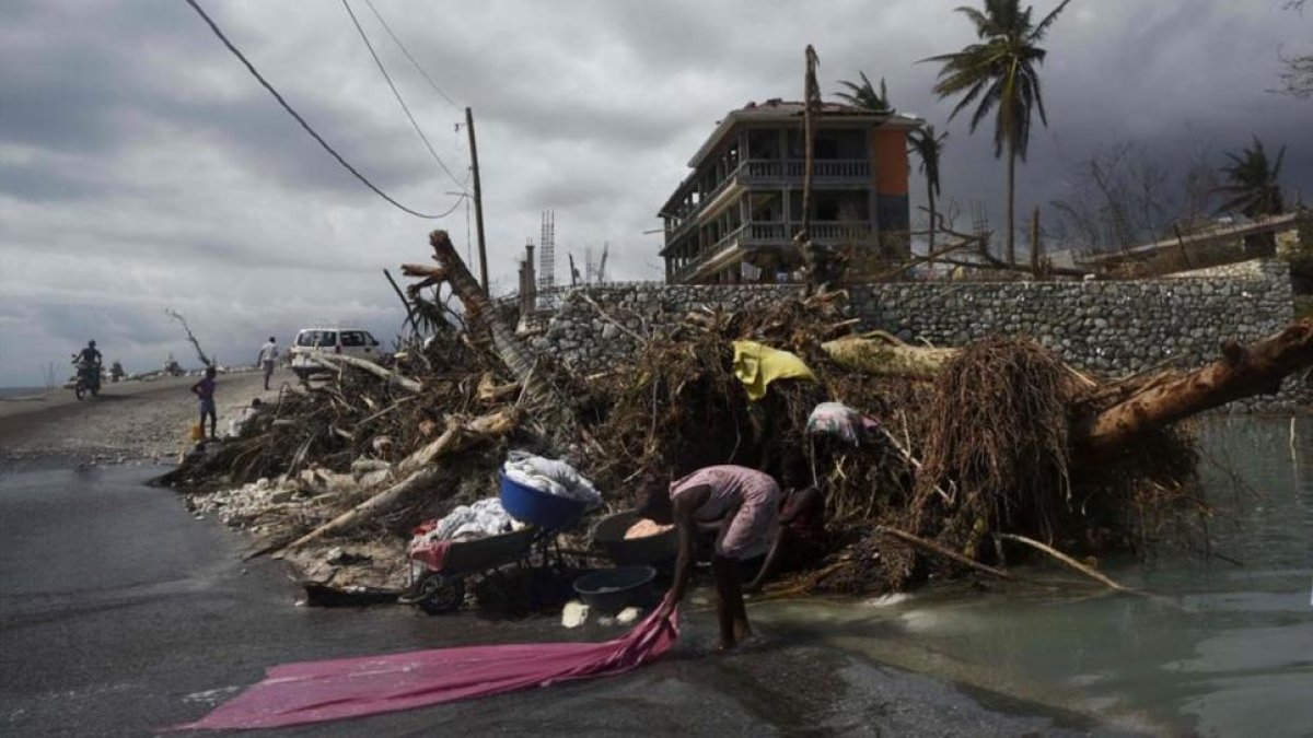 Una mujer lava ropa en las calles de Port-Salut, al suroeste de Puerto Príncipe, el 9 de octubre.-AFP / RODRIGO ARANGUA