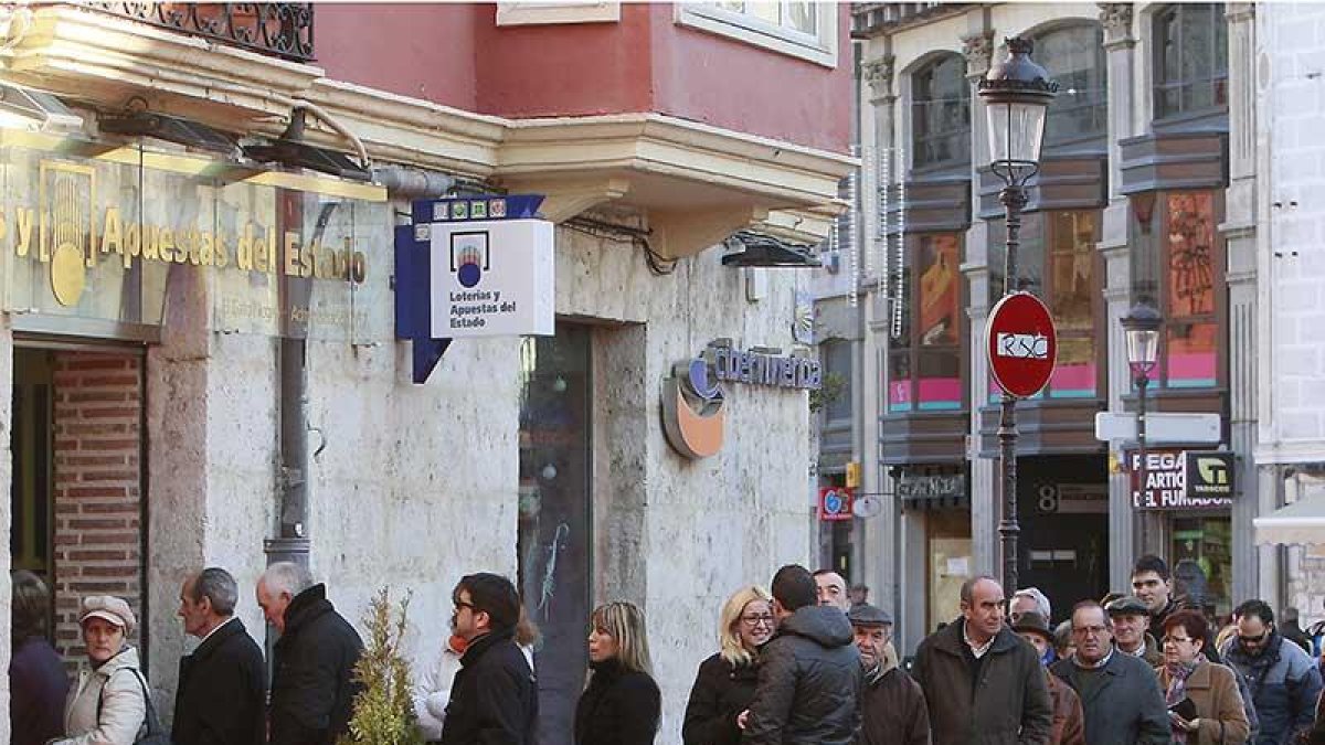 Burgaleses hacen cola a las puertas de una administración de lotería de la capital tras el sorteo de Navidad.-R. OCHOA