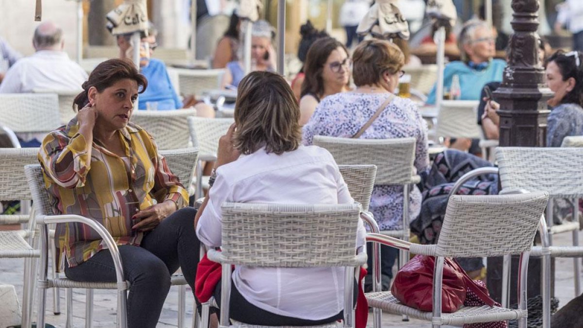 Varias personas disfrutan del buen tiempo en una terraza.