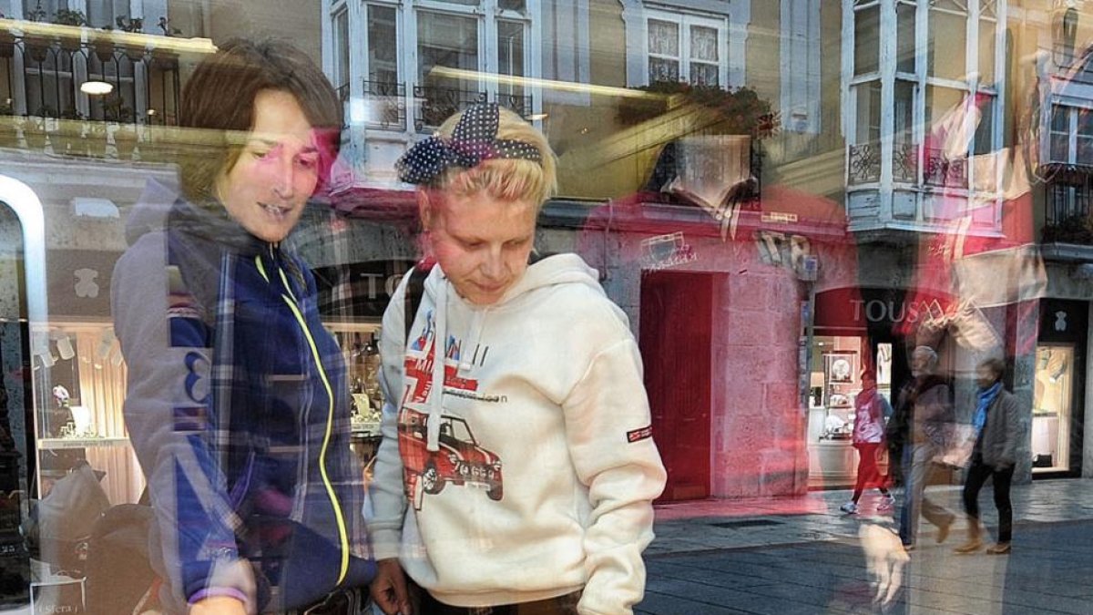 Dos personas observan el escaparate de un comercio en Burgos.-ISRAEL L. MURILLO