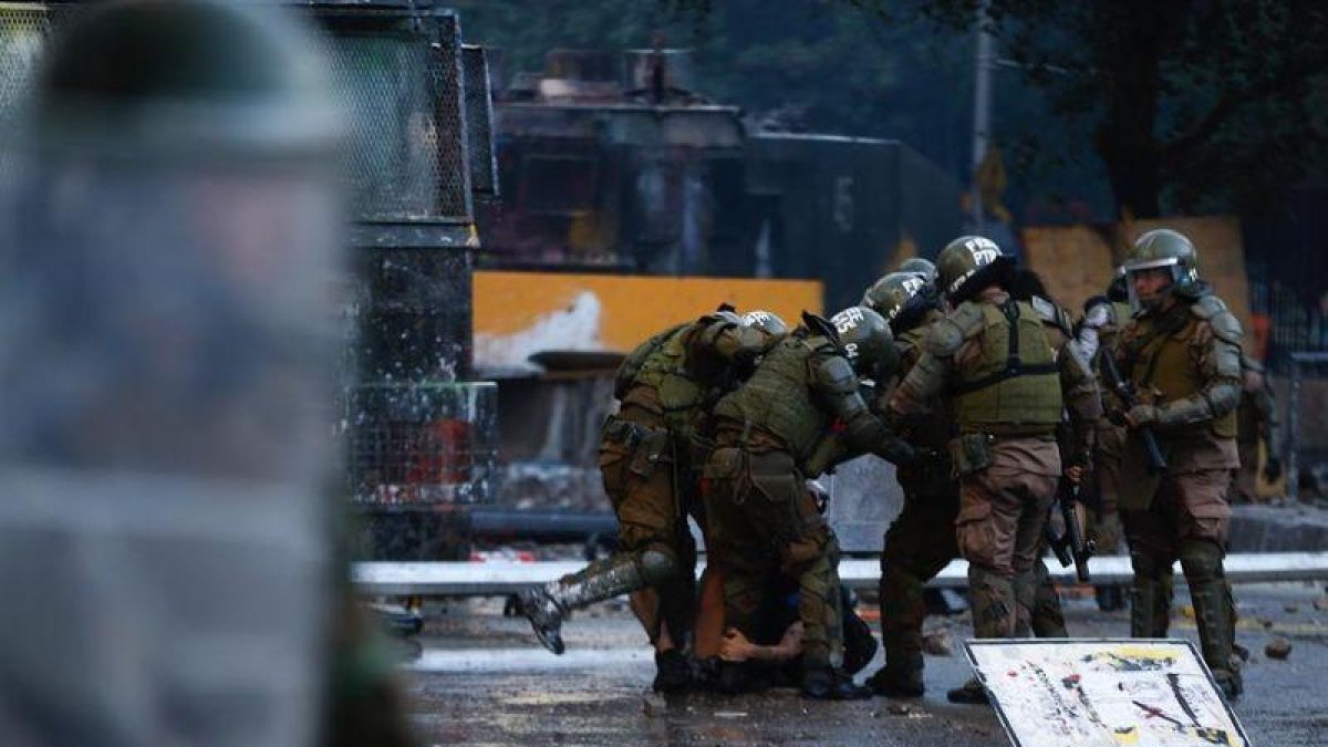 Fuerzas Especiales de Carabineros retienen a un manifestante este viernes en la Plaza Italia, rebautizada popularmente como “Plaza de la Dignidad”, durante una nueva jornada de movilizaciones y protestas, en Santiago (Chile).-EFE / ALBERTO VALDES