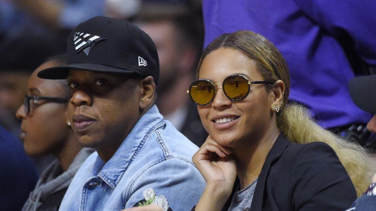 El rapero Jay Z (izq) y su esposa, la cantante Beyonce, asisten a un partido de la NBA.-AP
