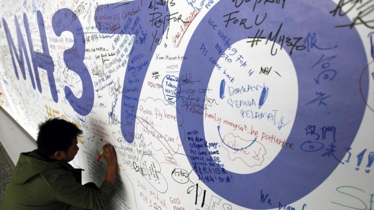 Un hombre escribe sus condolencias por las víctimas del vuelo MH370 de Malaysia Airlines en el aeropuerto internacional de Kuala Lumpur en marzo del 2014.-MAK REMISSA